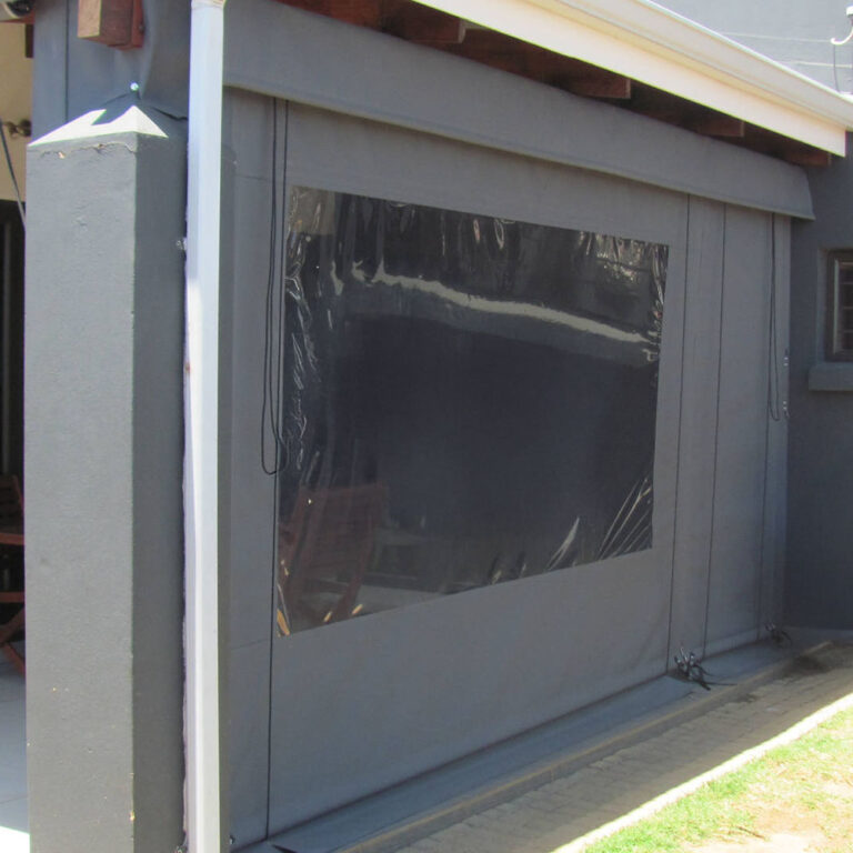 Grey canvas blind with a clear PVC window panel closing a patio opening