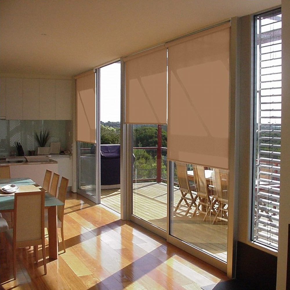 Peach roller blinds drawn over full-height glazing beside a dining table and balcony