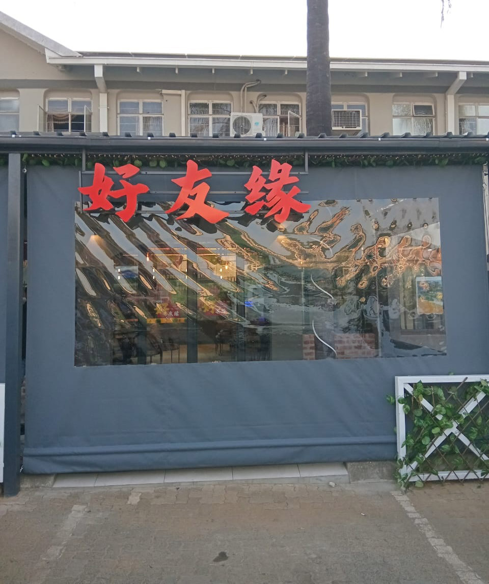 Grey drop blind with a wide clear PVC window enclosing a restaurant frontage