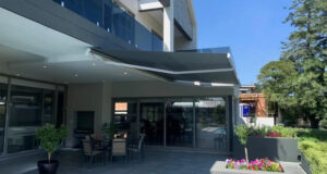 Grey retractable fold-arm awning extended over a patio, made and fitted by Patio SA