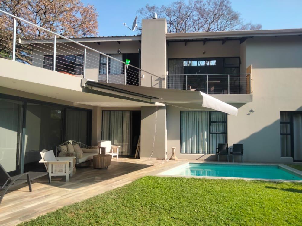 Retractable awning extended over a garden next to a swimming pool