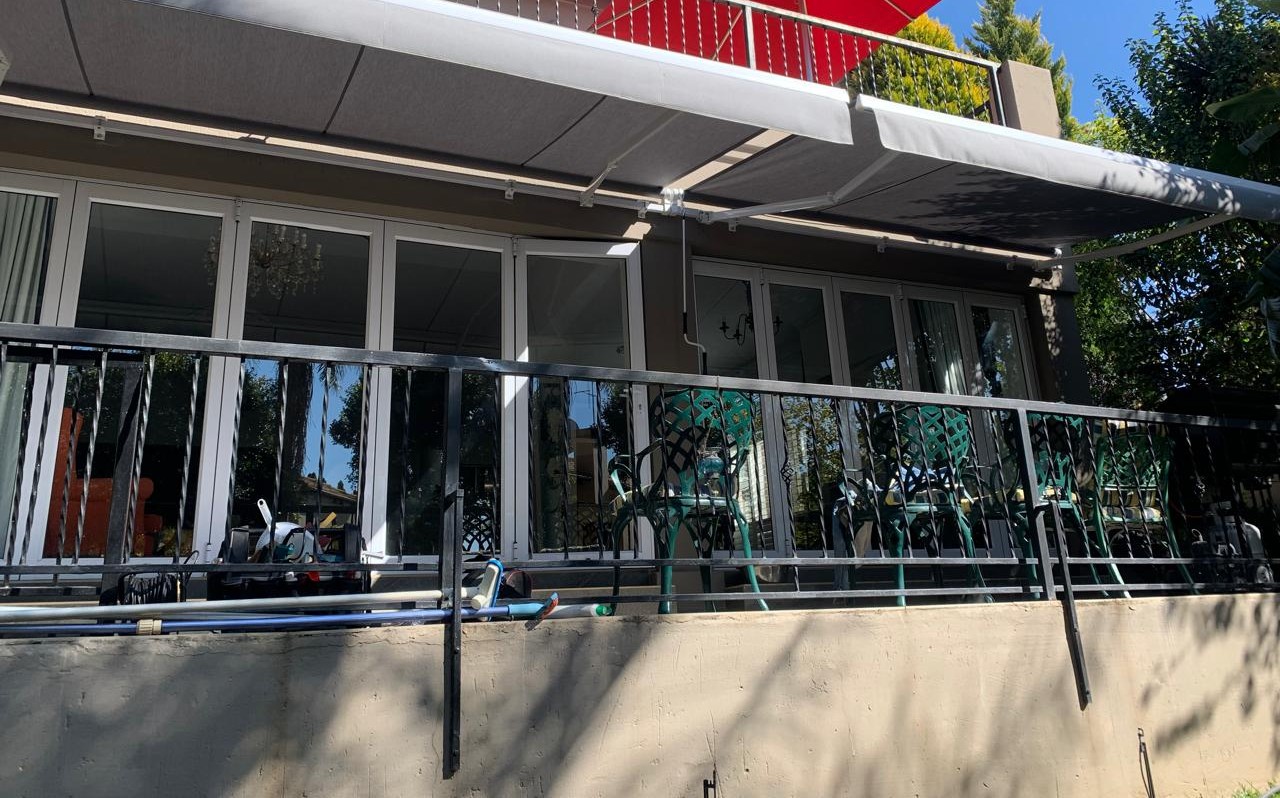 Retractable fold-arm awning shading a patio and balcony on a Johannesburg home