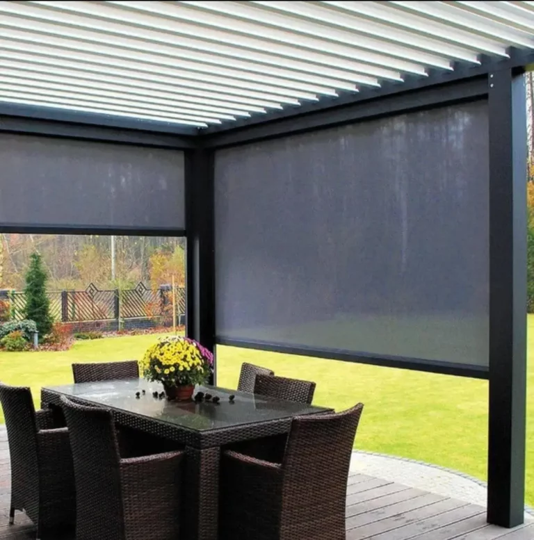 Charcoal drop blinds lowered under a white louvre pergola over a timber deck