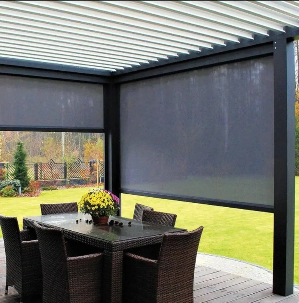 Charcoal drop blinds lowered under a white louvre pergola over a timber deck